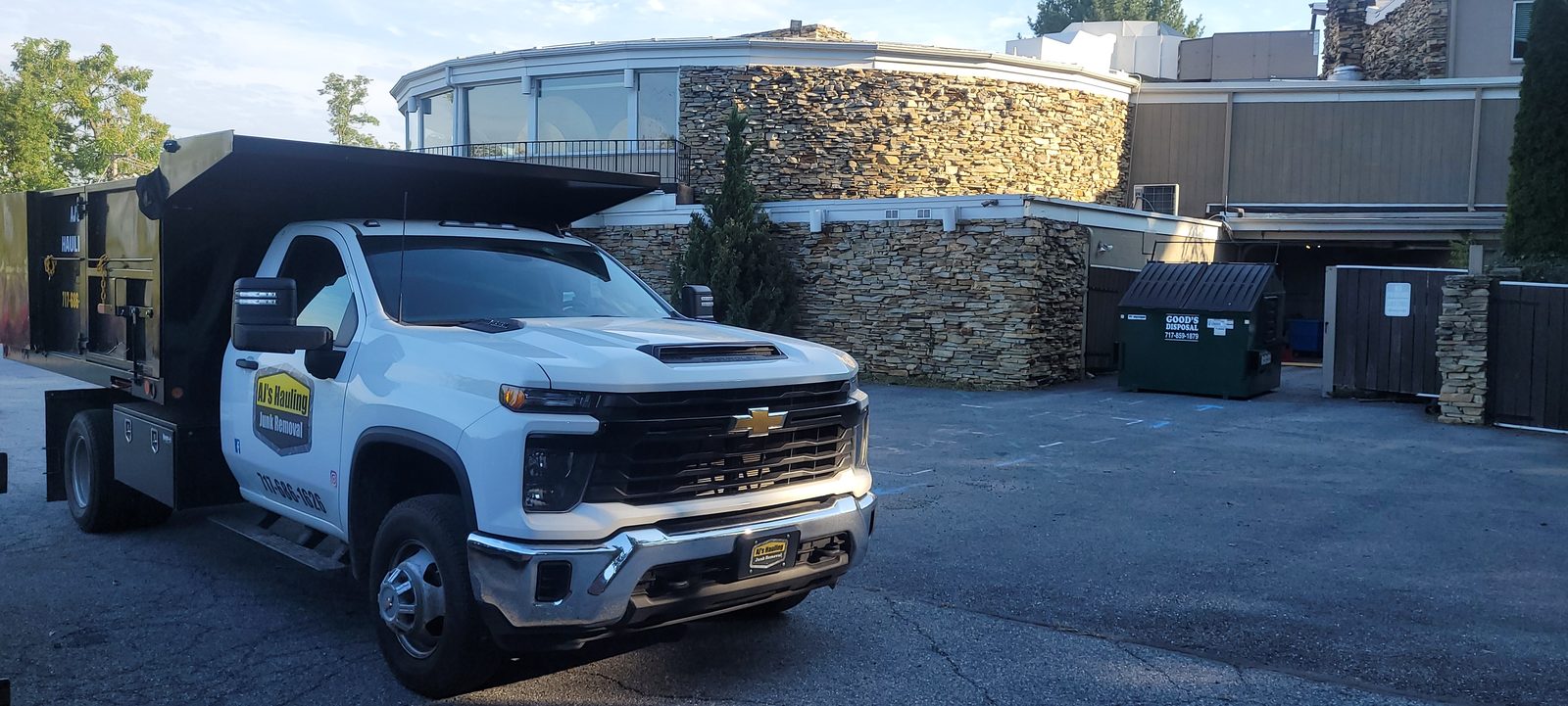 A white AJ's Hauling dump truck parked outside a stone building in Central Pennsylvania