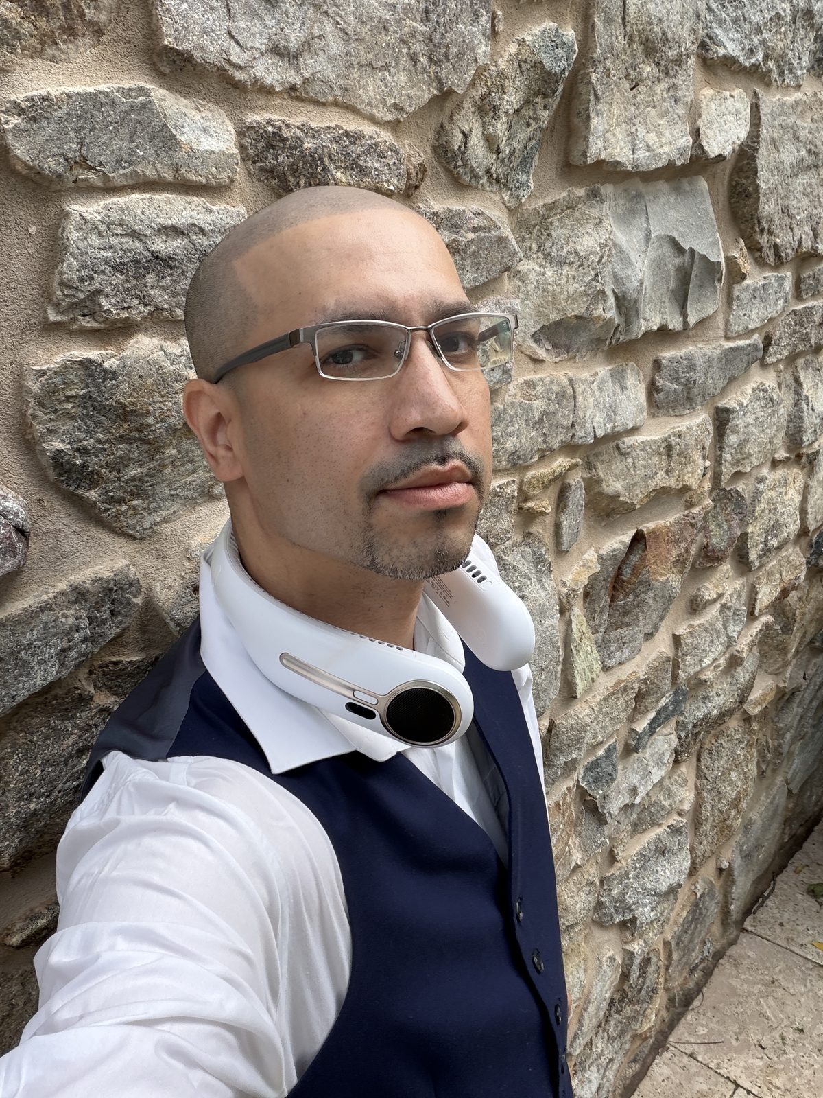 Angel Rivera, DJ Stream, founder of Stream DJ & Events, in a white shirt and navy vest against a stone wall