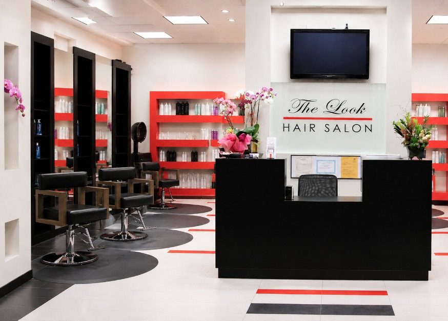 Inside The Look Hair Salon in Glendale: black styling chairs, red product shelves and the front desk under the salon's name