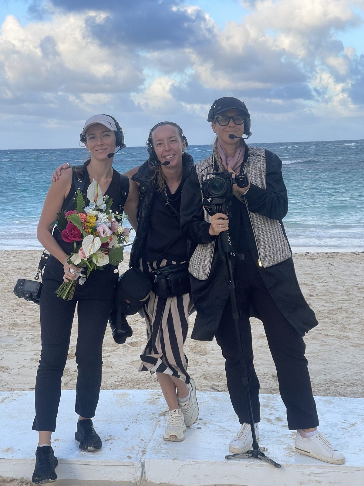 The Kumantsova Productions photo and video team with cameras and a bouquet on a Punta Cana beach