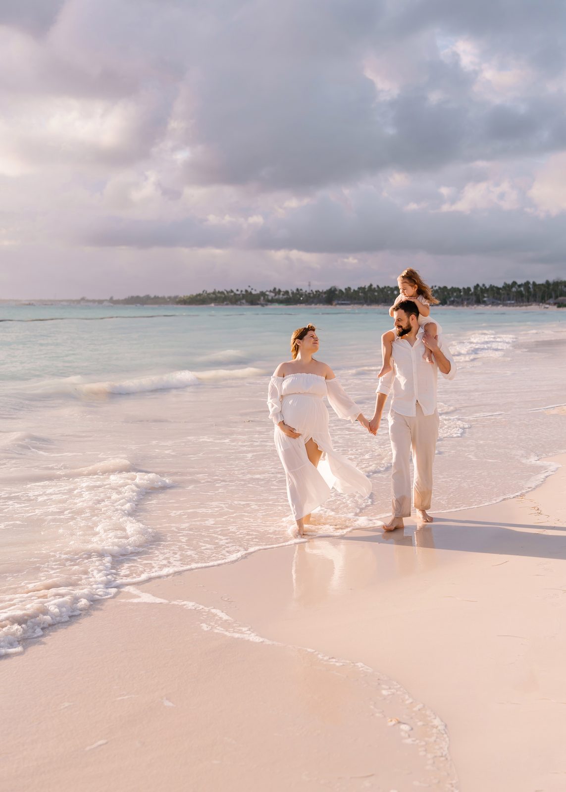 A family in white walking along the shoreline at sunset in Punta Cana