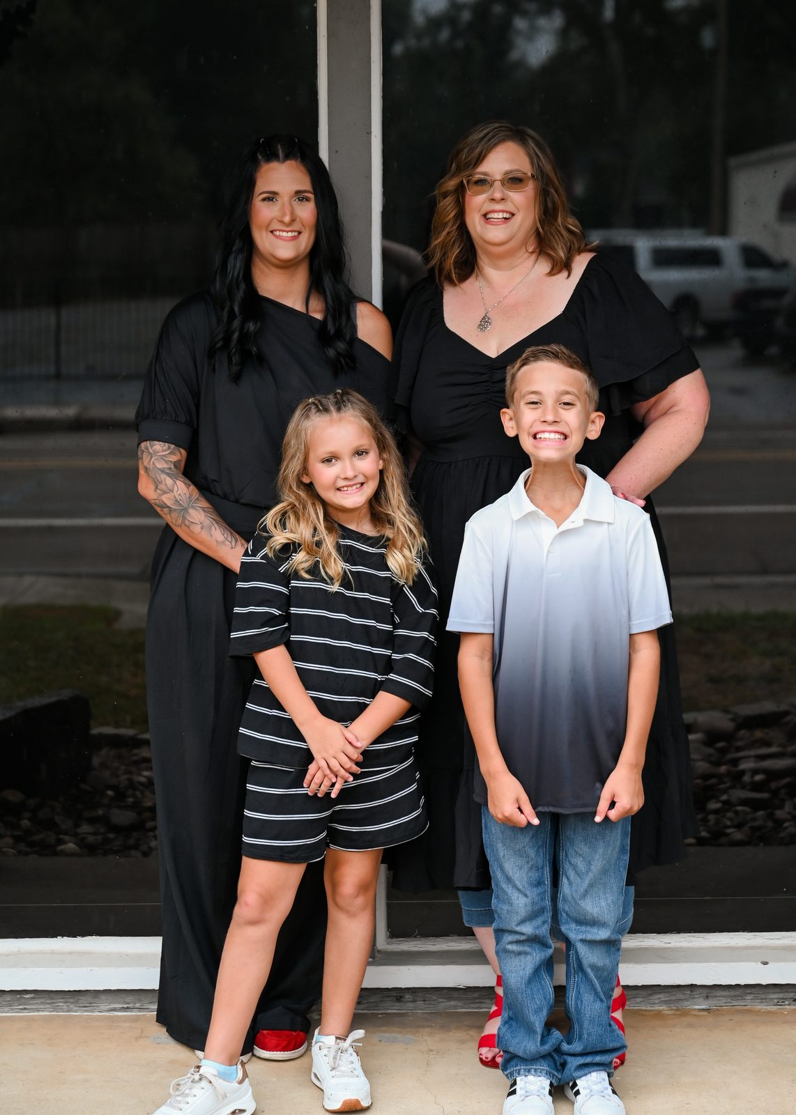 April Barnard standing with a young woman and two smiling children in front of a glass storefront