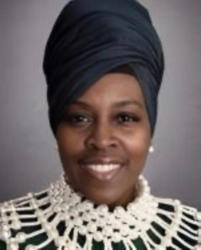 Studio portrait of Athenae Evans in a navy head wrap and a pearl collar against a grey backdrop