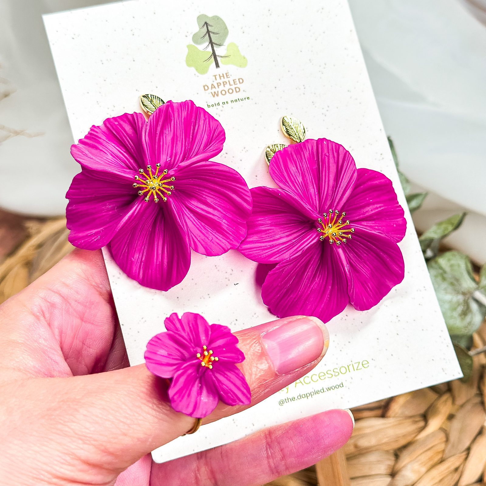 A hand holding a card of magenta polymer clay flower earrings from The Dappled Wood