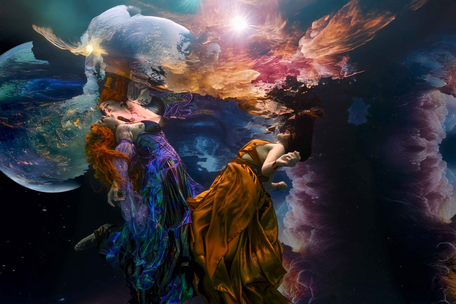 Exploring the Cosmos, an underwater fine art image by Bruce Campbell of two models in flowing gowns drifting among planets and nebulae