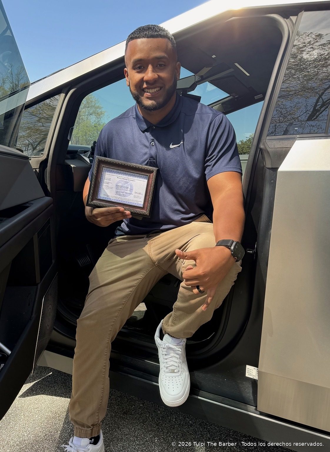 Adoní Cuevas holding the barber license he earned after training under Carlos Turpeau Ramos