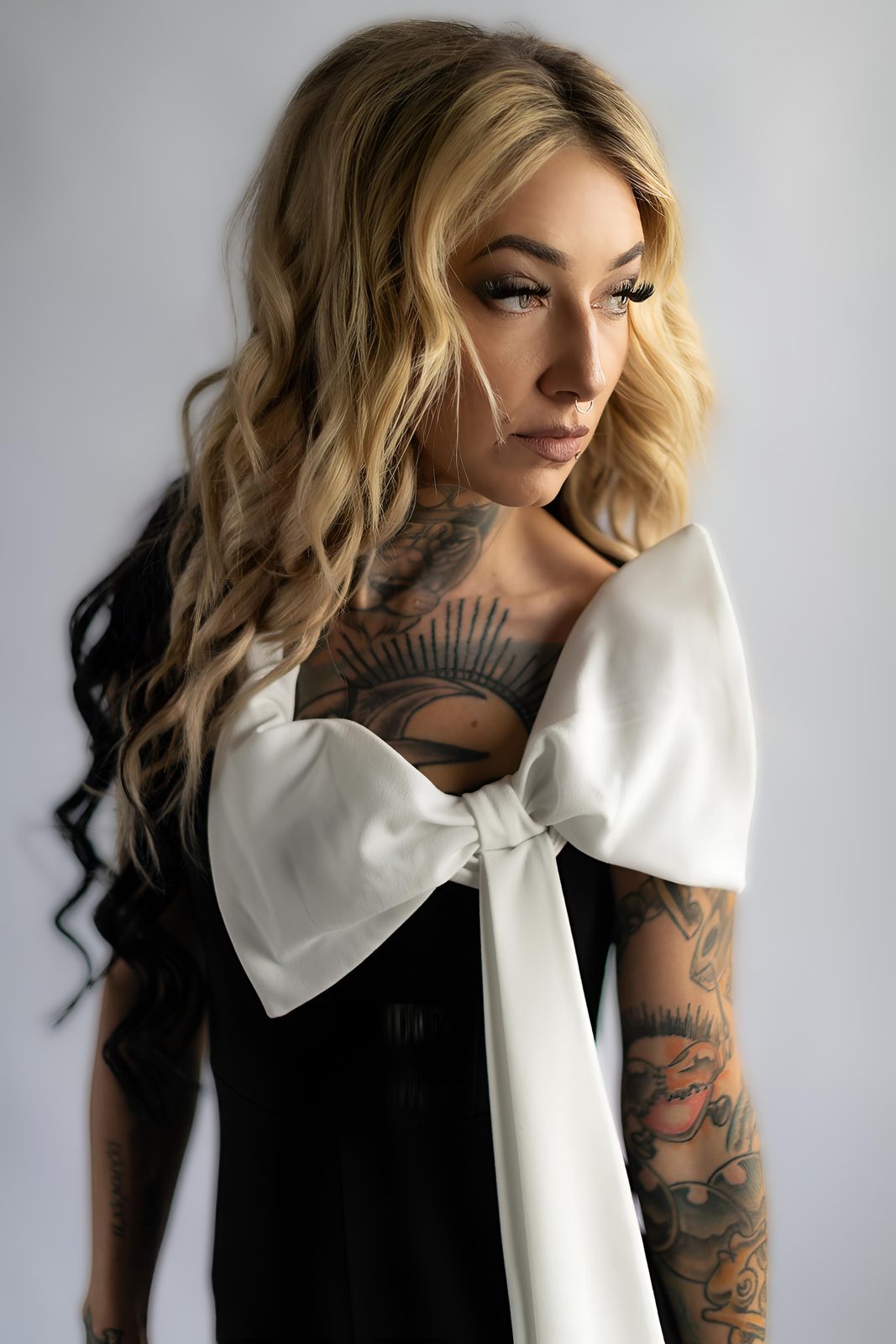 Chelsea Elle looking to the side, in a black dress with an oversized white bow