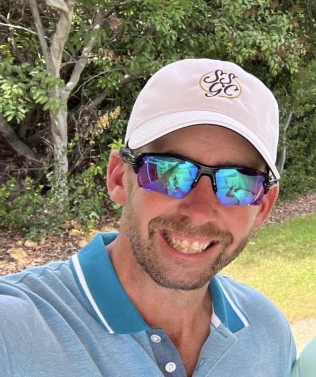 Chris Smeal, founder of Future Champions Golf, smiling in a white golf cap and sunglasses on a course