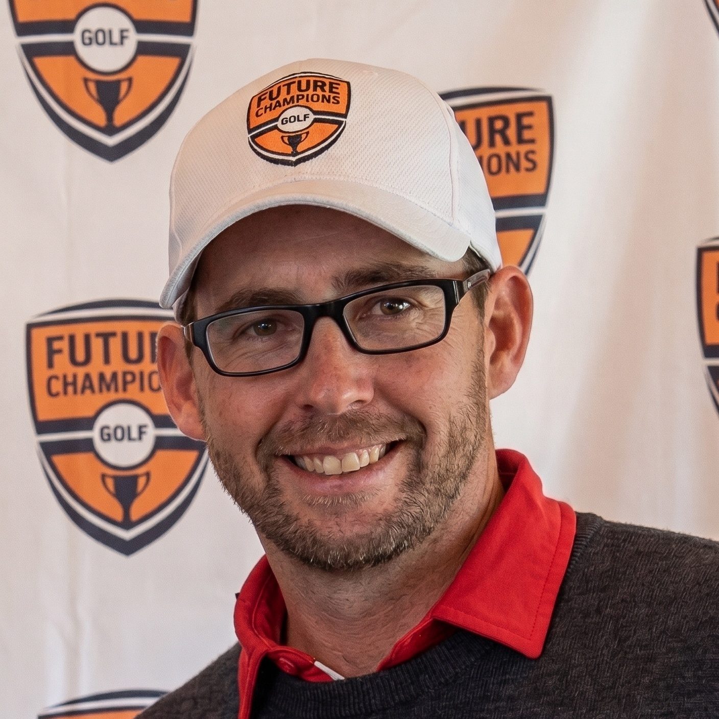 Chris Smeal, founder of Future Champions Golf, smiling in a white golf cap and sunglasses on a course