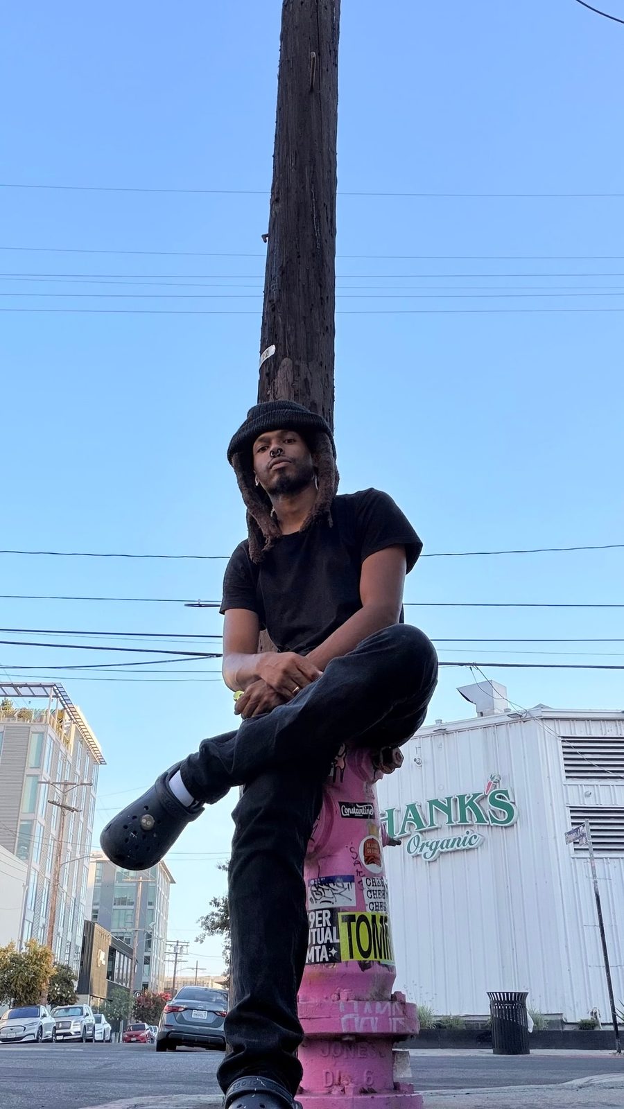 Clinton Robinson Jr. sitting on a pink fire hydrant on a Los Angeles street corner
