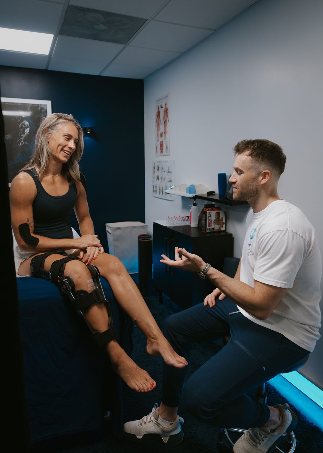Stephen Preyer talking with a smiling client in a knee brace who is recovering from ACL surgery