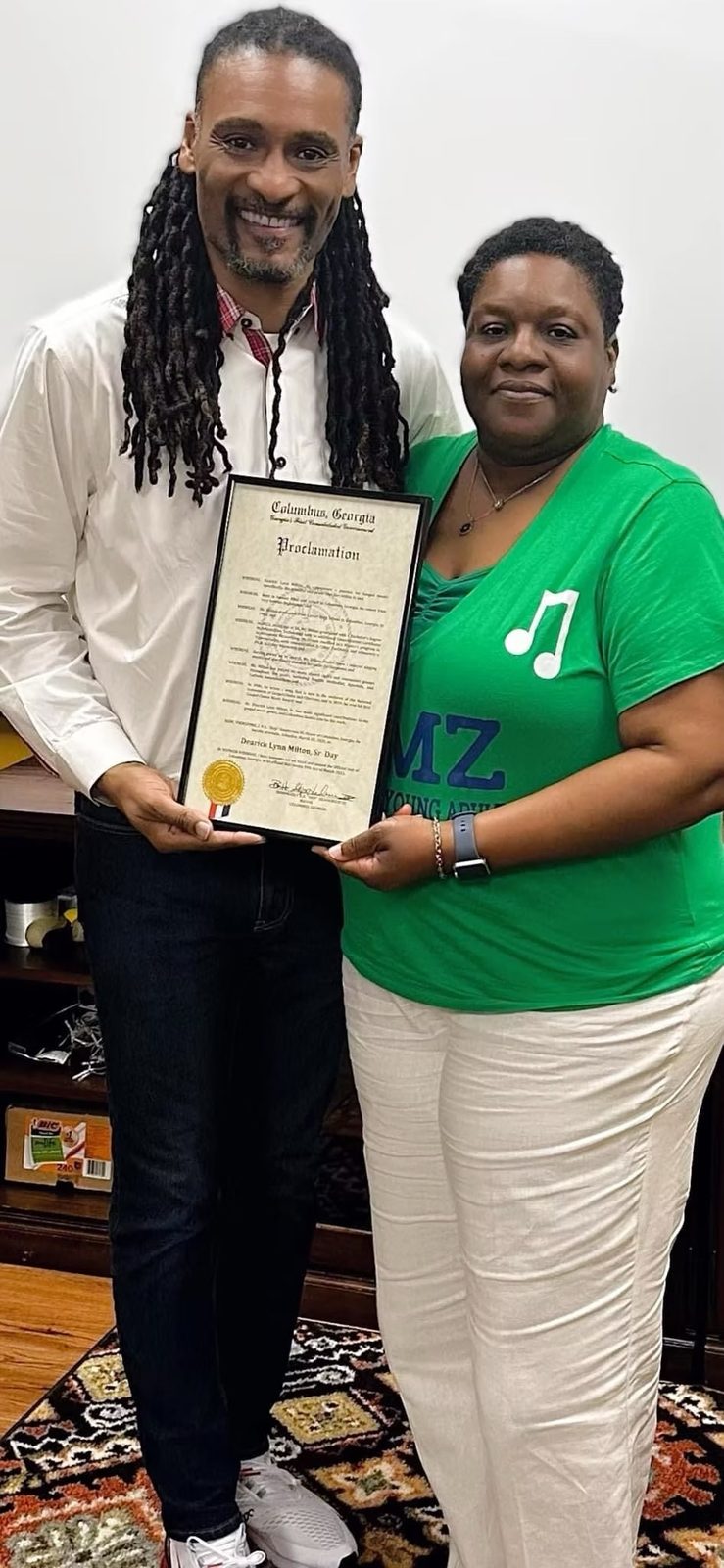 Dearick Milton holding a framed proclamation from the City of Columbus, Georgia