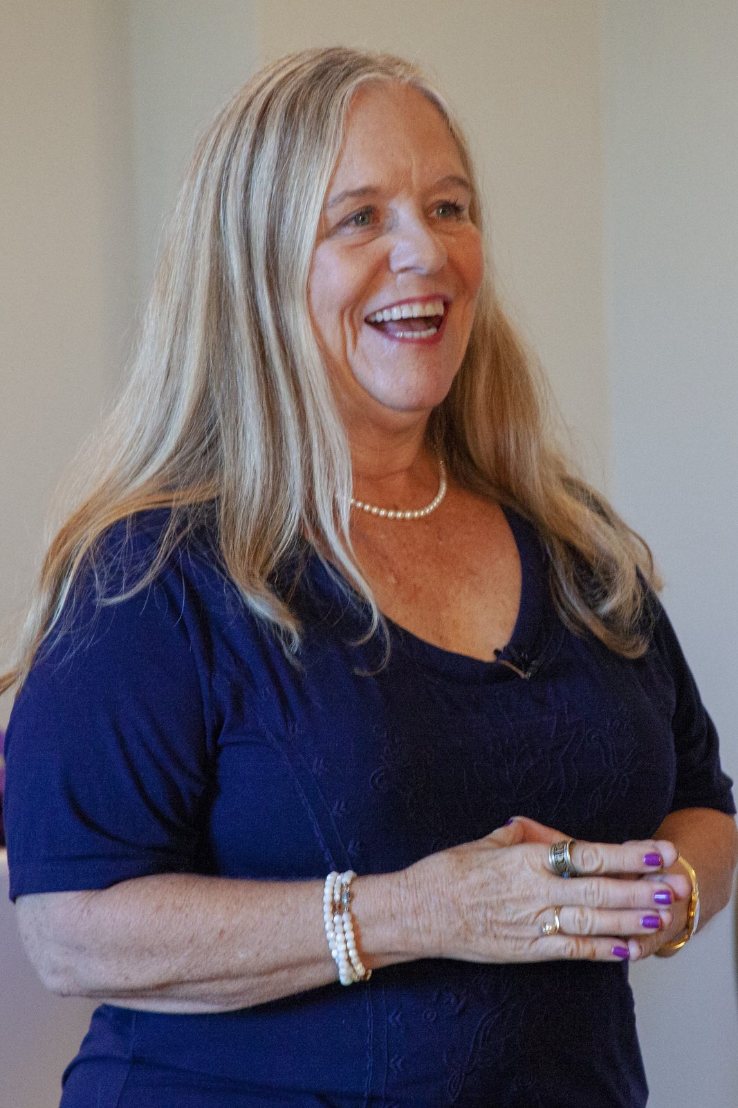 Dianne Allen, founder of Visions Applied, laughing in a navy top and pearl necklace