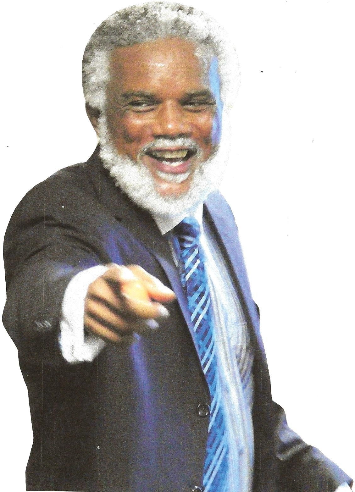 Donald L. Dowridge, Jr. laughing and pointing toward the camera in a dark suit and striped blue tie