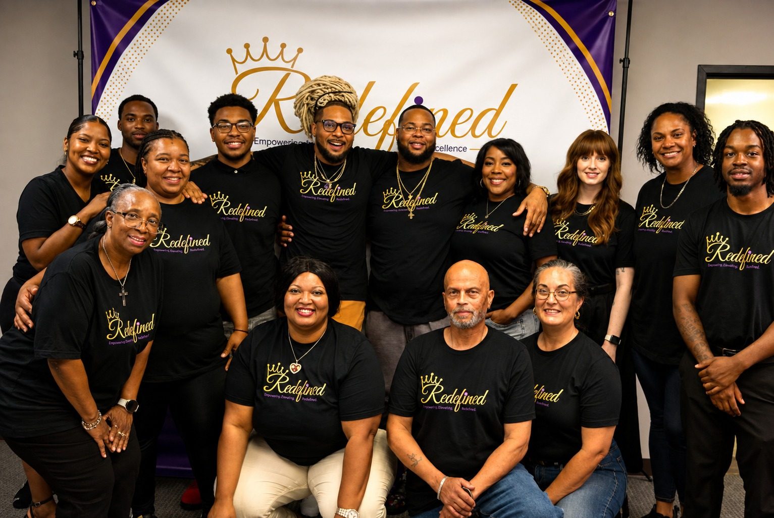 The Redefined team in matching black Redefined shirts in front of the Redefined banner