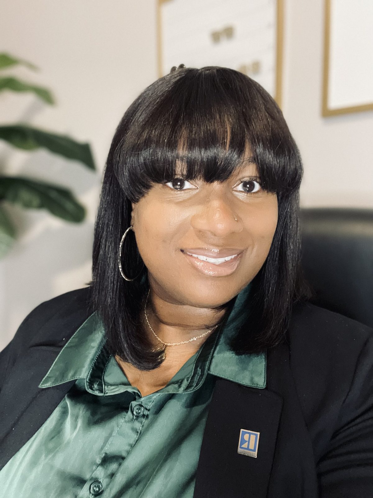 Ebony Vick, founder of Empower.Execute.Elevate., smiling in a green satin blouse and black blazer with a Realtor pin