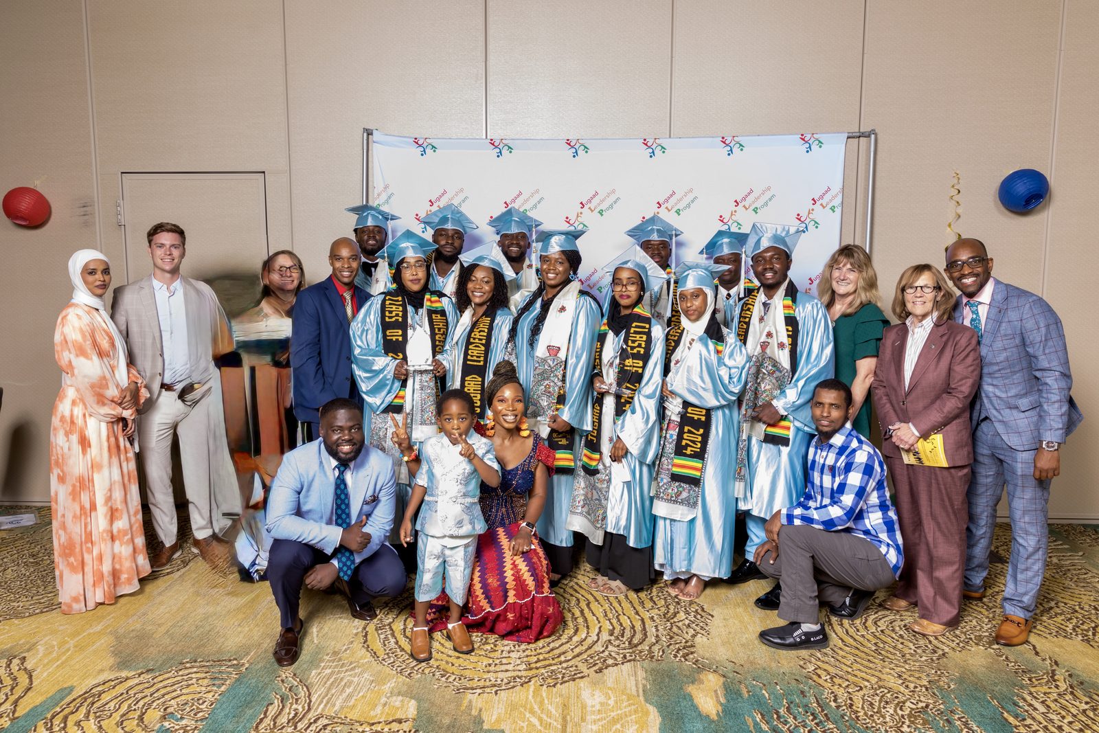 A Jugaad Leadership Program graduating class in caps and gowns posing with mentors and supporters