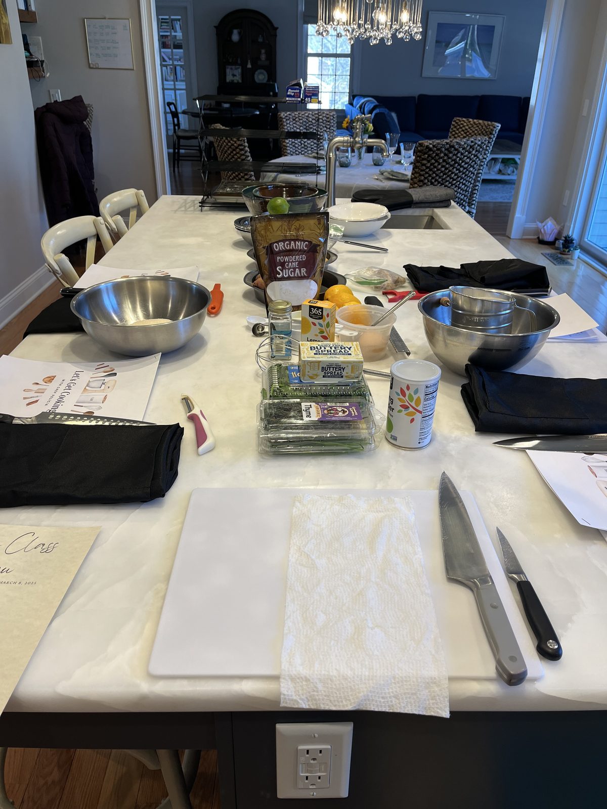 A dining table set with cutting boards, mixing bowls and knives for an in-home cooking class