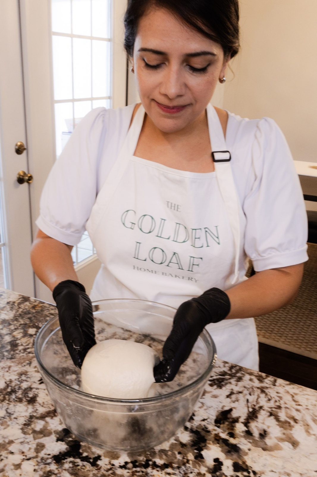 Gaby Miller in a Golden Loaf apron shaping a ball of sourdough in a glass bowl