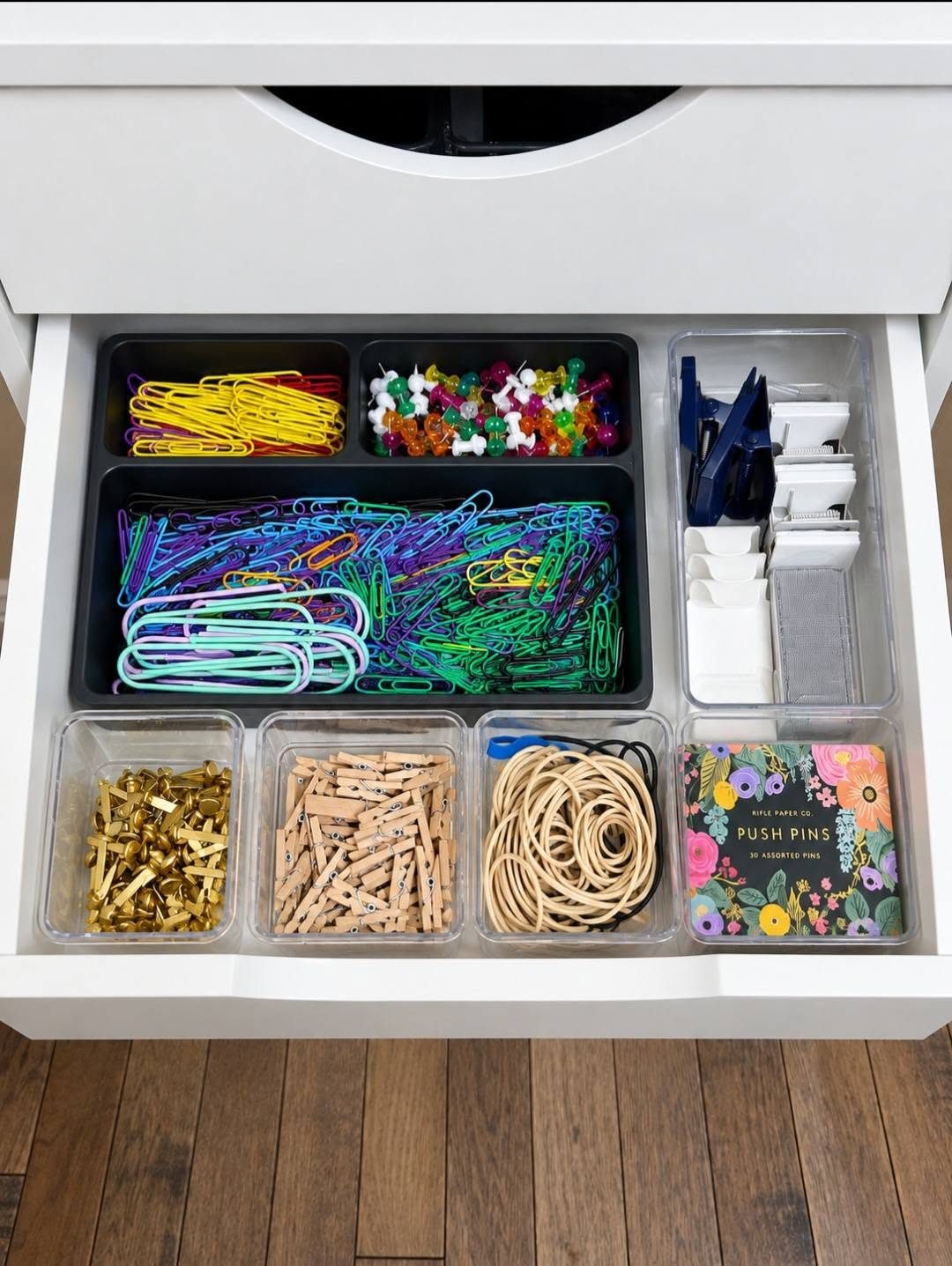 An office drawer organized by Grace to Organize, with paper clips, push pins and rubber bands sorted into trays