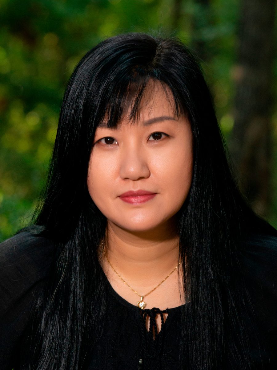 Hailey Herrera, watercolor batik artist in College Station, Texas, in a black top against a soft green woodland background