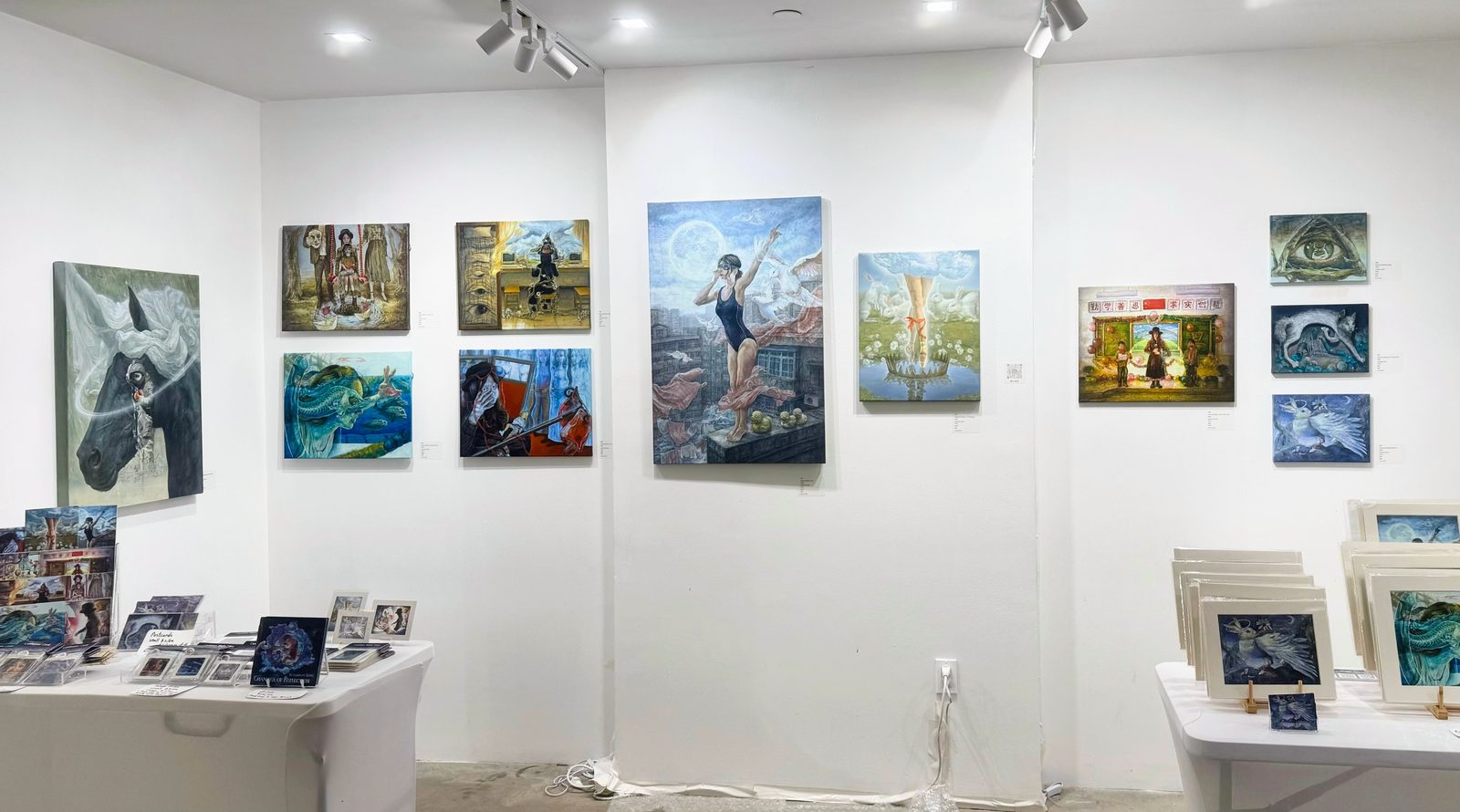 Huaixuan Xiang's art fair booth, with her paintings hung on white walls and prints and cards displayed on tables