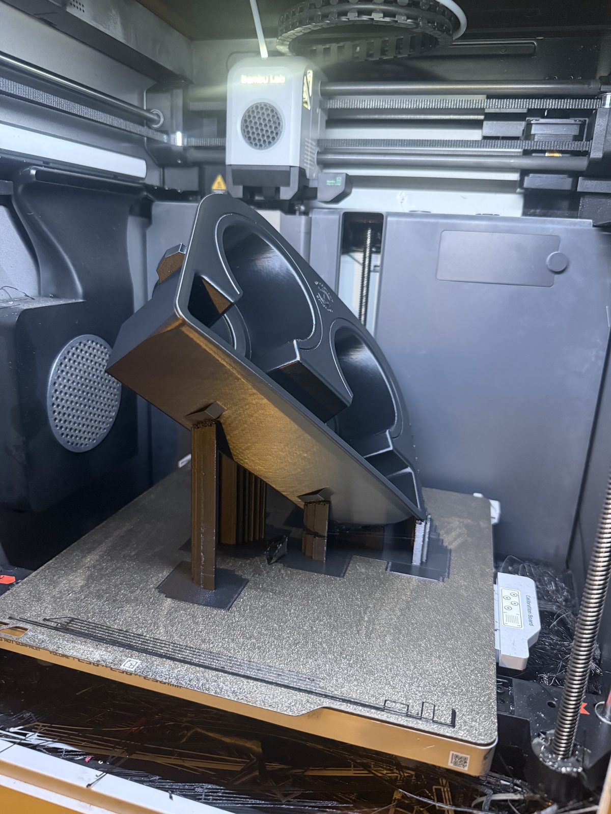 A 3D-printed cupholder part on the build plate of a Bambu Lab printer