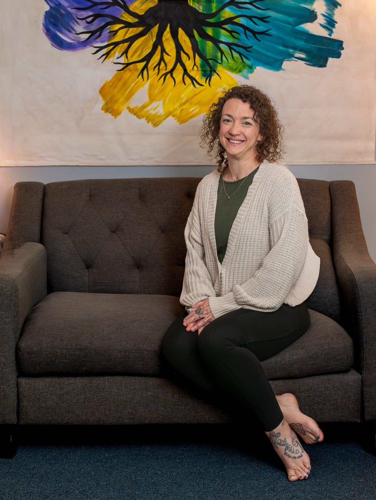 Jeanette Lamonde seated beneath the Inner Roots Wellness tree artwork