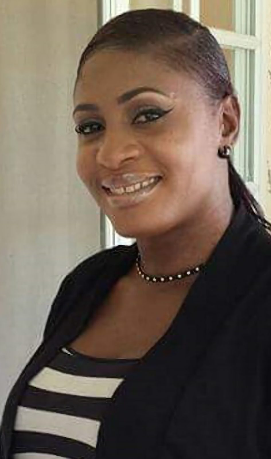 Jillian Guy, founder of Weddings in Paradise, smiling in a dark blazer and striped top