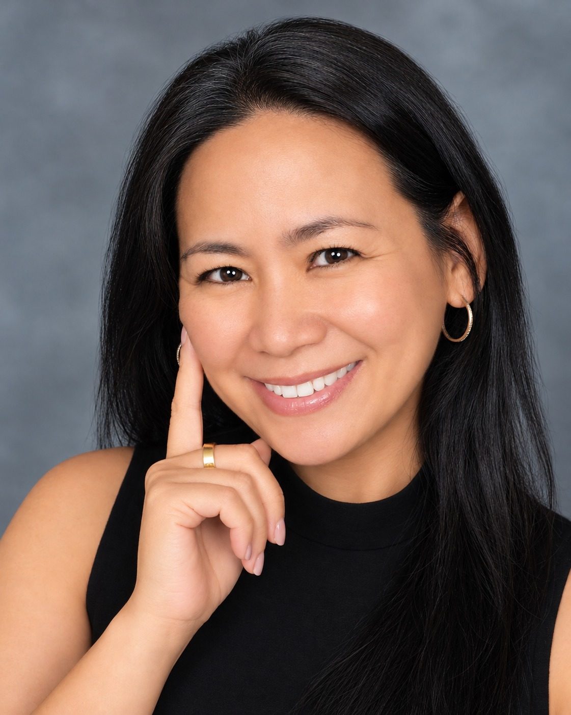 Dr. Johnimel Bianco, general dentist and owner of All Care General Dentistry, smiling in a black sleeveless top against a grey studio backdrop