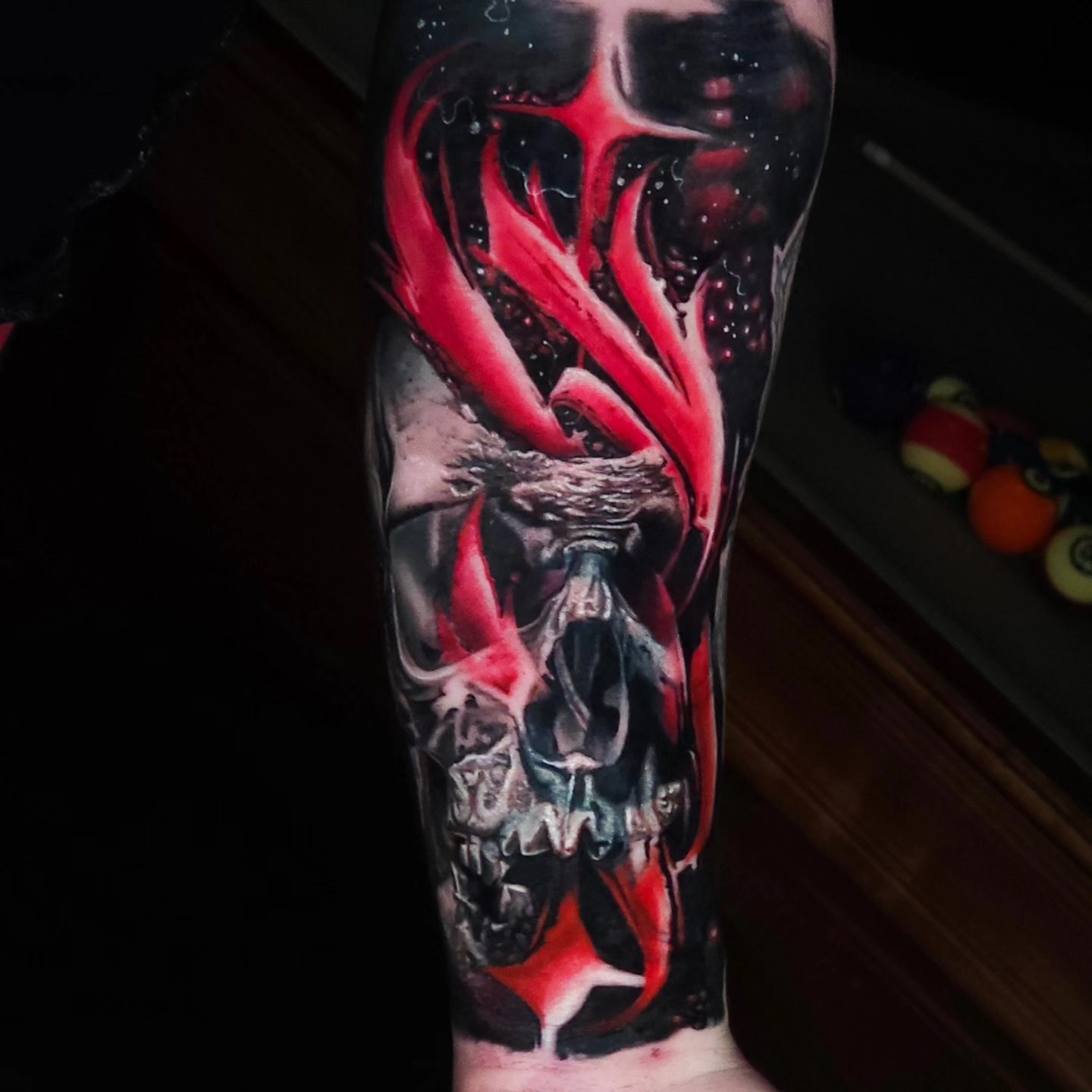 A red and black skull forearm tattoo by Philly Joe