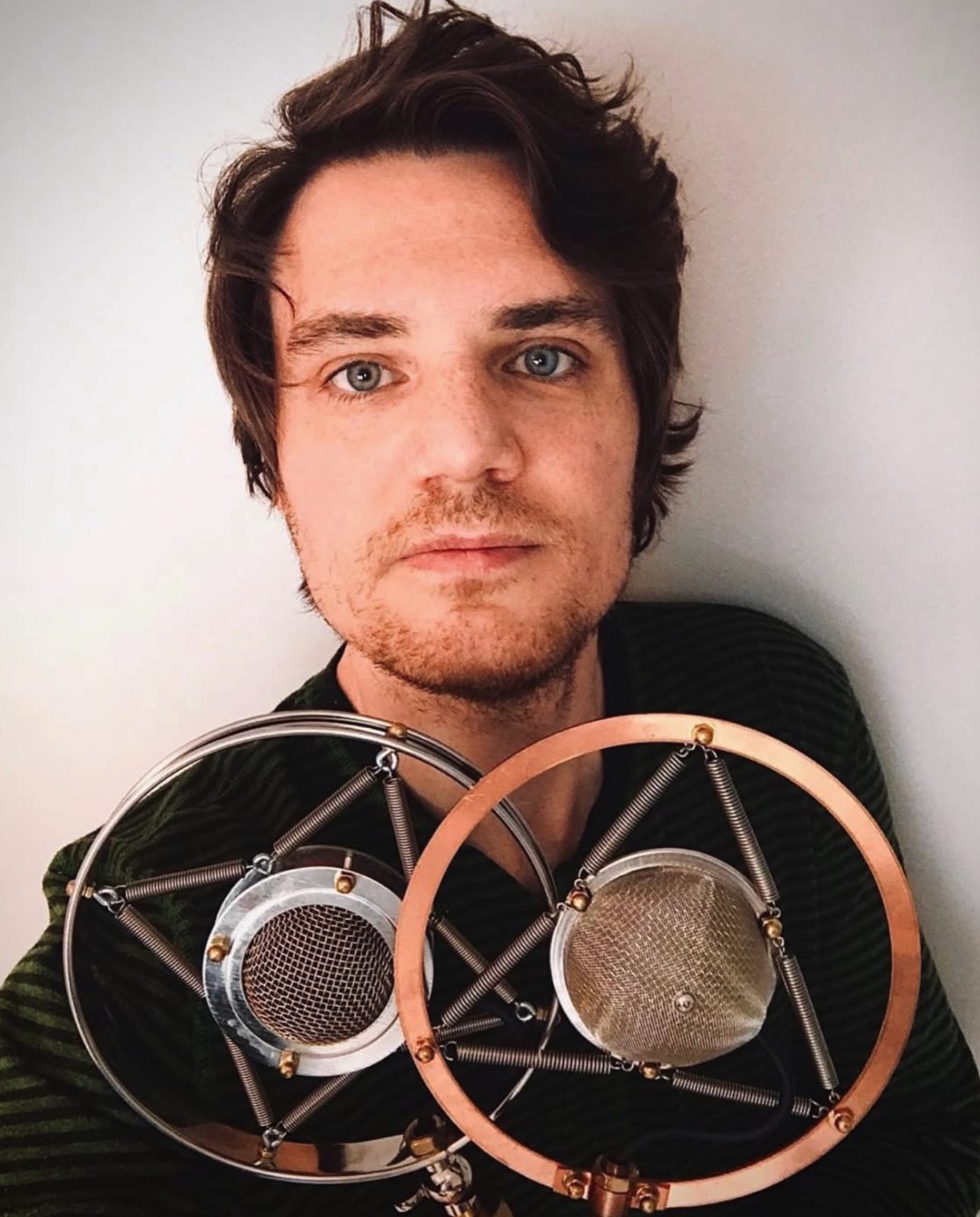 Joshua M. Lutz, founder of Lutz Multimedia and JML Studios, holding two vintage spring-mounted microphones