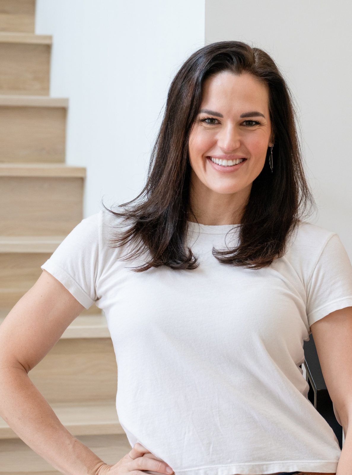 Kathryn Currey, founder and CEO of Friday Personal Assistants, smiling in a white T-shirt with one hand on her hip