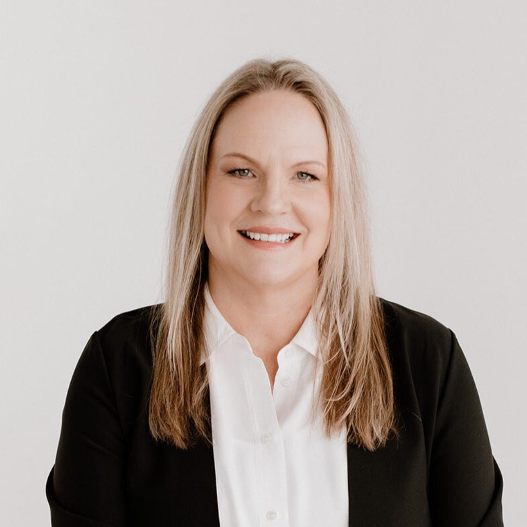 Keli Jakel, founder of Organized by Keli & Co., smiling in a black blazer and white shirt against a plain light background