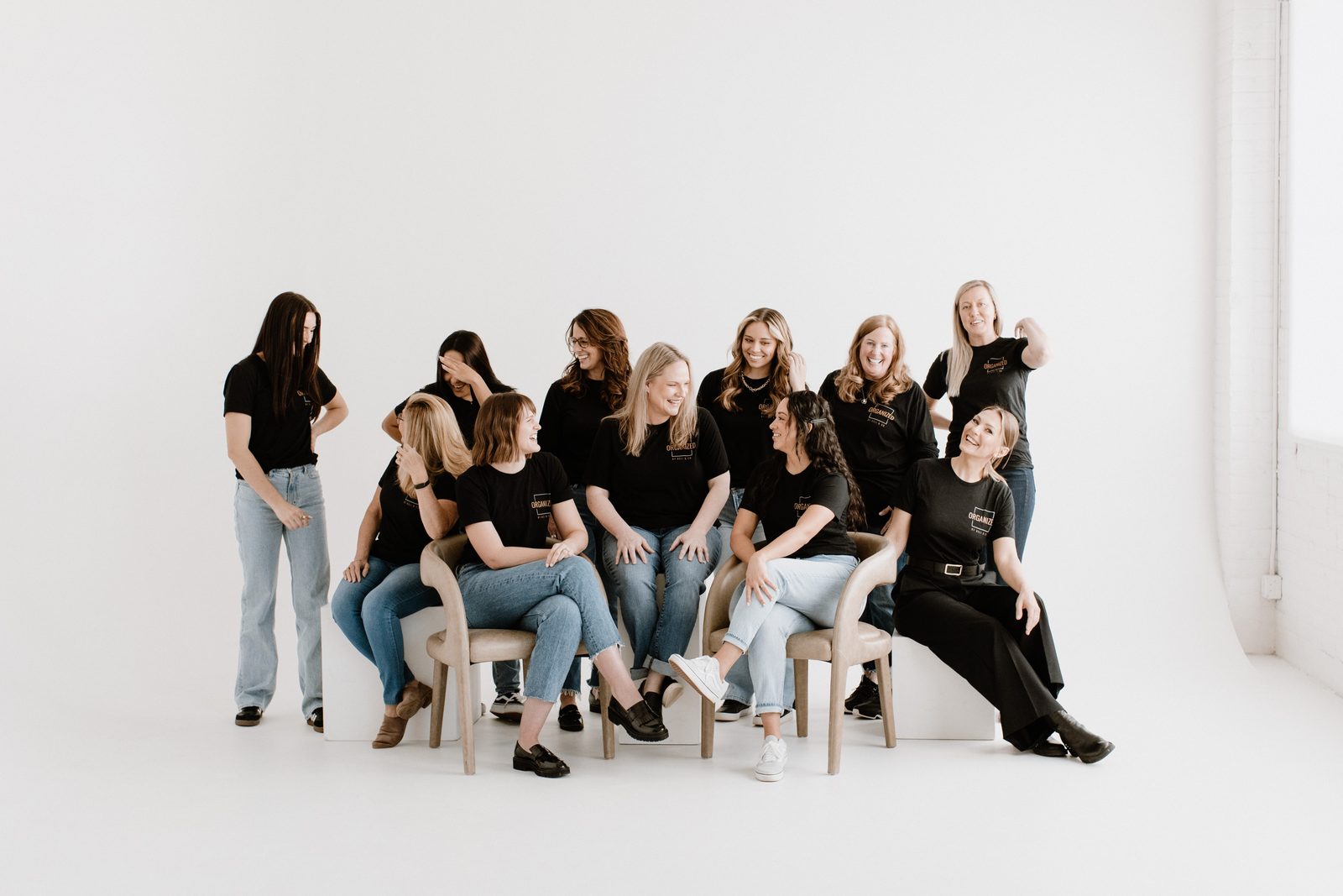 The Organized by Keli & Co. team in matching black shirts, seated and standing together in a bright white studio