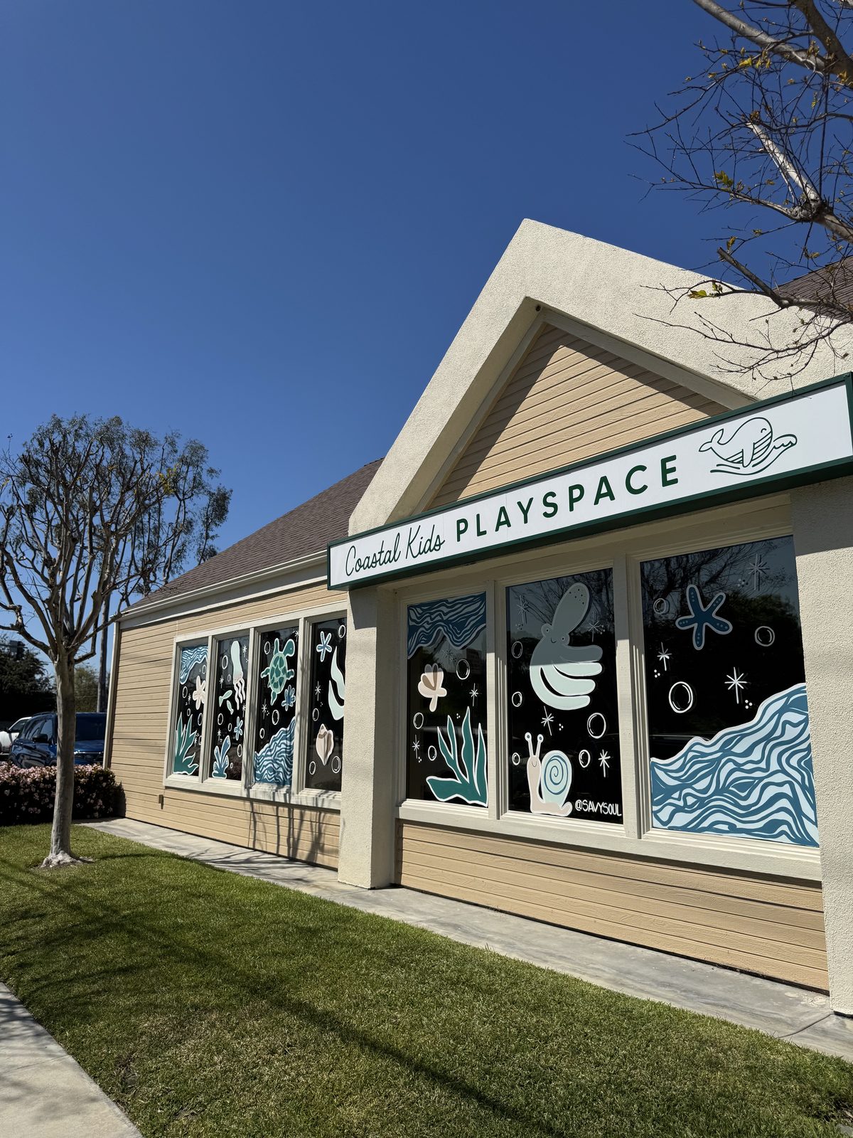 The Coastal Kids Playspace storefront in Long Beach, its windows painted with ocean waves, starfish and sea creatures under a blue sky