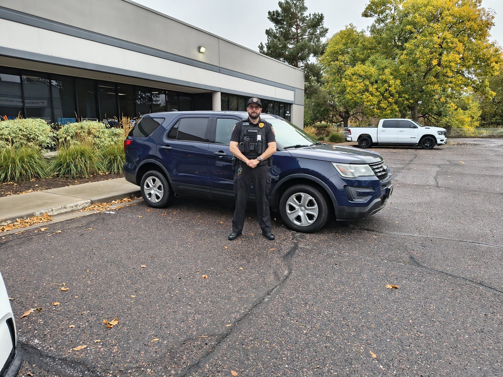 Mark Schneider in uniform and a tactical vest standing in front of a Patrol Guard Security Services patrol SUV