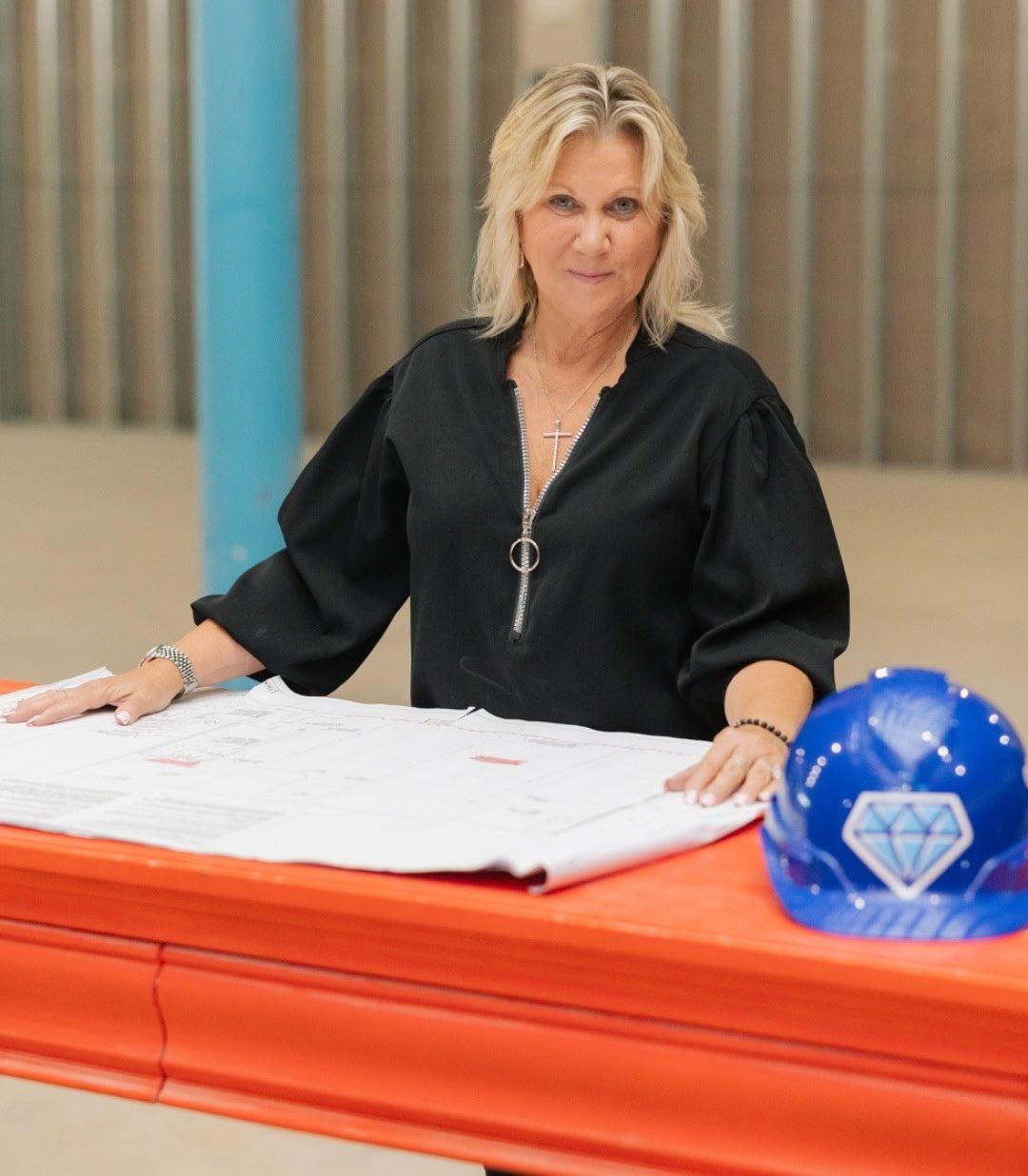 Pat Miller, founder and president of Blue Diamond Construction in Jackson Township, New Jersey, standing over a set of drawings beside a blue Blue Diamond hard hat