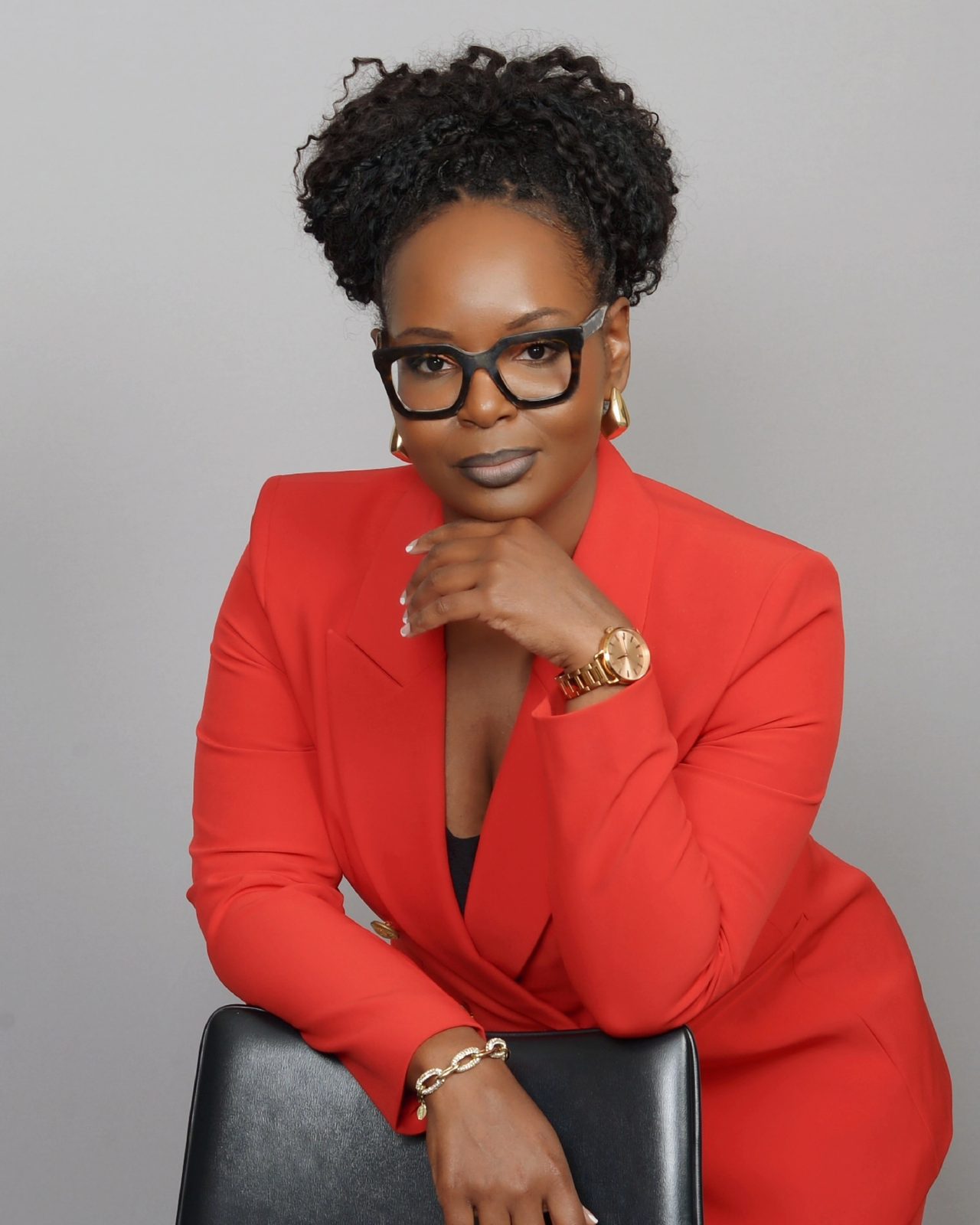 Priscilla Peete, founder and CEO of Peete Vending, in a red blazer and black glasses with her chin resting on her hand