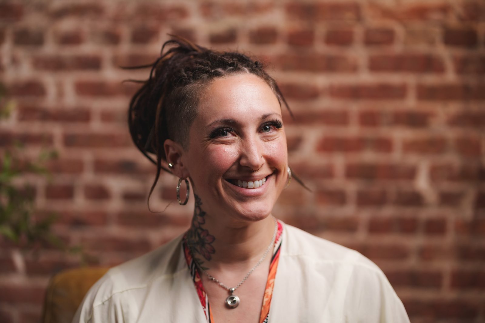 Sarah Pezak, owner of Diamond in the Ruff Pet Spa, smiling in front of a brick wall in a cream blouse