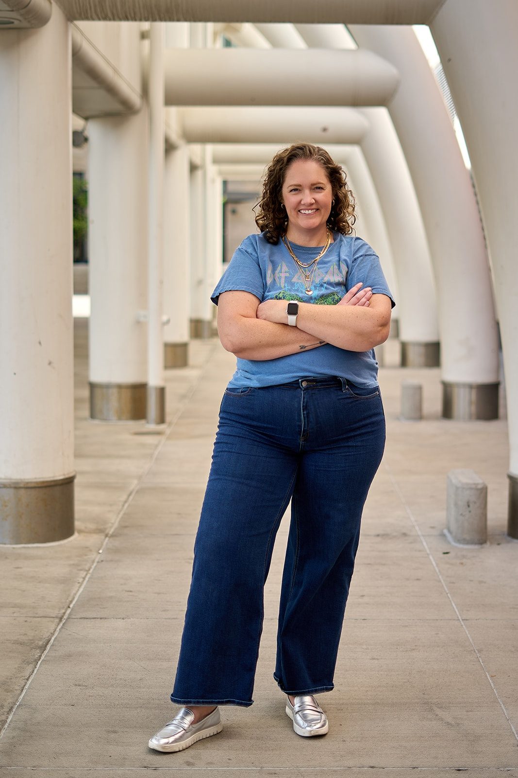 Shannon Gross standing with her arms crossed under a row of white concrete arches in Denver