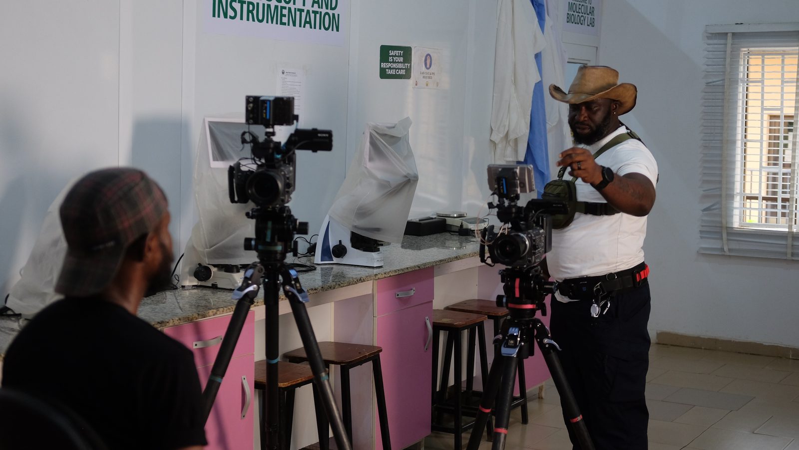 Simpa Samson setting up two cameras on tripods for an interview in a laboratory