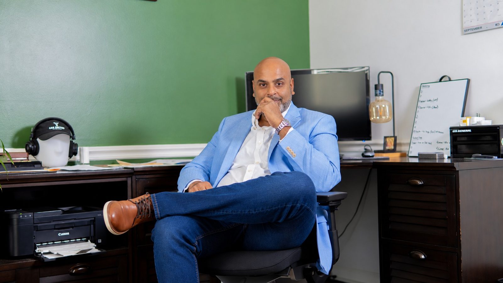 Sri Gadde in a light blue blazer seated at his desk in the CarDoctorATL office