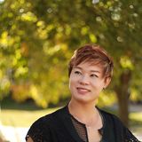 Grace Liu, owner of Infinity Massage in Kansas City, smiling outdoors in a black lace cardigan and green top