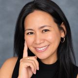 Dr. Johnimel Bianco, general dentist and owner of All Care General Dentistry, smiling in a black sleeveless top against a grey studio backdrop