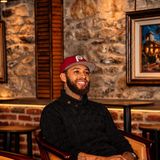Joseph Thomas, known as Philly Joe, founder of Philly Joe Tattoo Studio in Newtown, Pennsylvania, smiling in a red Phillies cap and black sweater