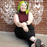 Lillian London, founder of London Cleaning Services in Kansas City, smiling in front of a painted brick mural
