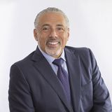 Marcus Hernandez, president of Hernandez Accounting Solutions, smiling in a navy suit and purple tie