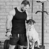 Matt Hitzhusen, owner of HITZ Fitness, standing beside one of the gym dogs sitting on a plyo box