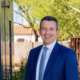 Oleg Bortman, co-founder of The Brokery, smiling in a blue suit and patterned tie outside in Phoenix, Arizona